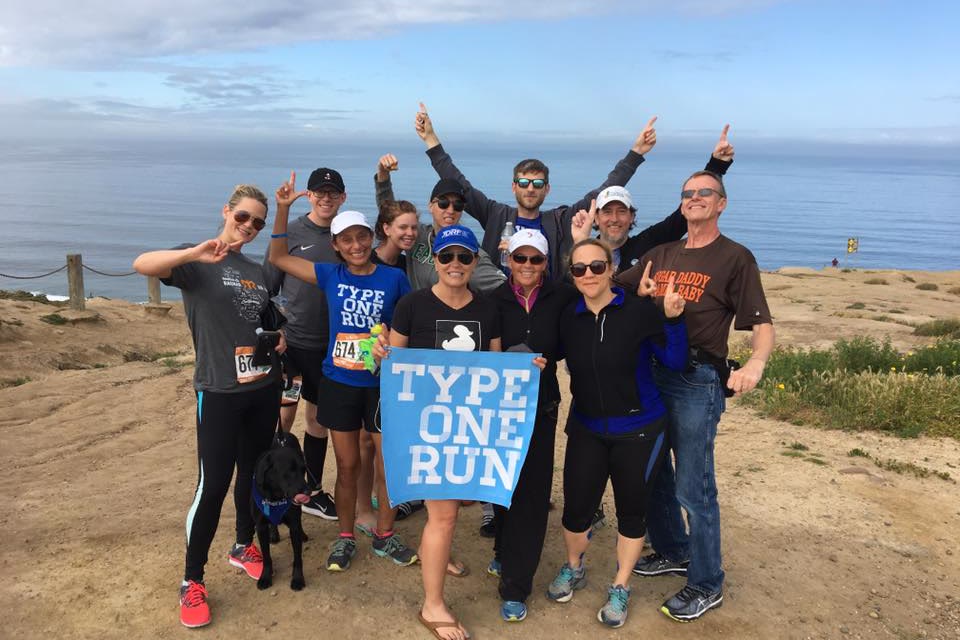 A Type One Run group on a coastal bluff holding the chapter banner, the ocean behind them.