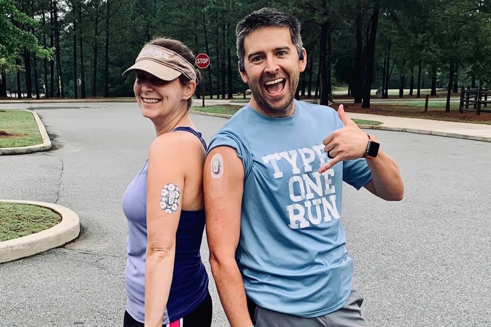 Two runners paused on a road, comparing the glucose sensors on the backs of their arms.